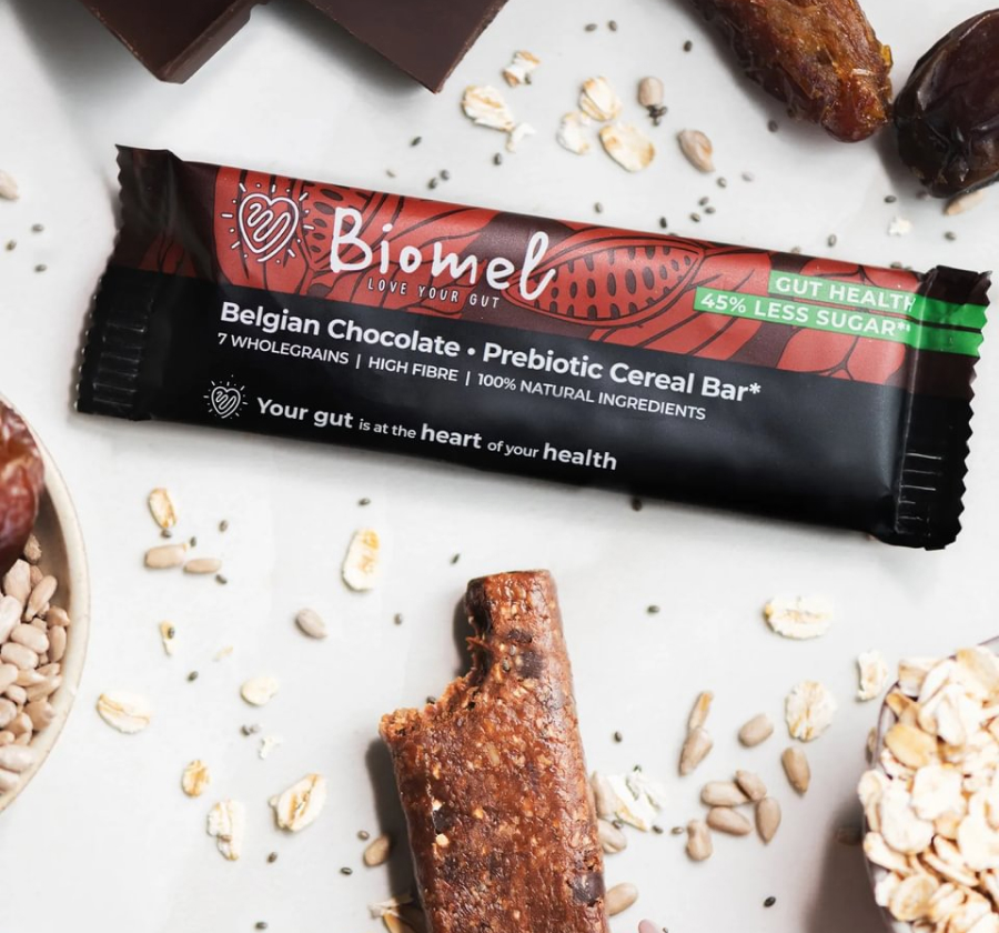 Biomel Belgian Chocolate Prebiotic Cereal Bar surrounded by seeds, oats, and dates.