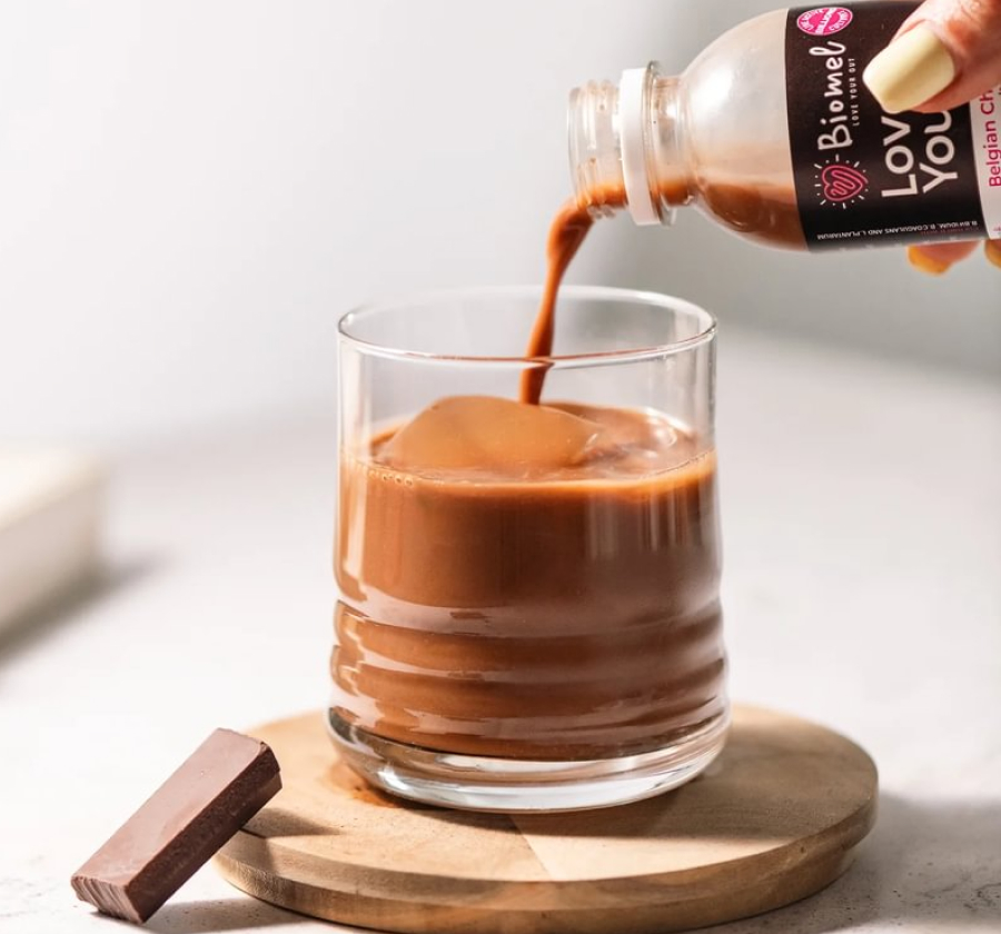 Chocolate drink being poured into a glass with a chocolate piece beside it.