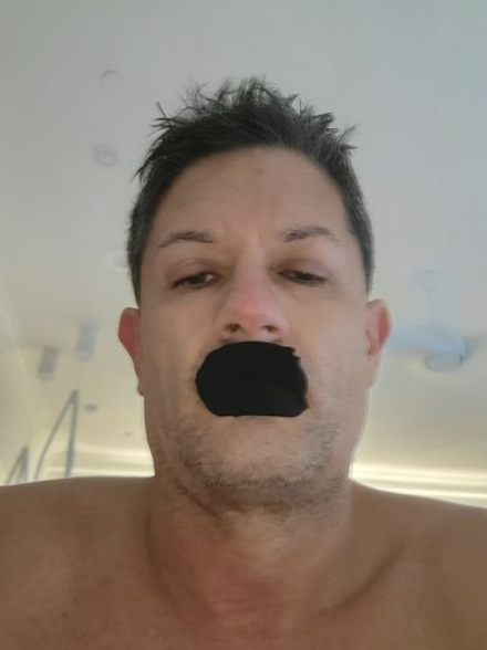 Person with black tape over mouth, indoors.