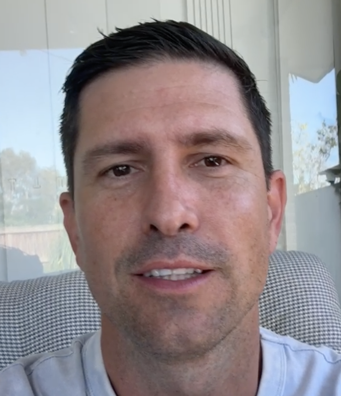 A person sitting indoors with a neutral expression.
