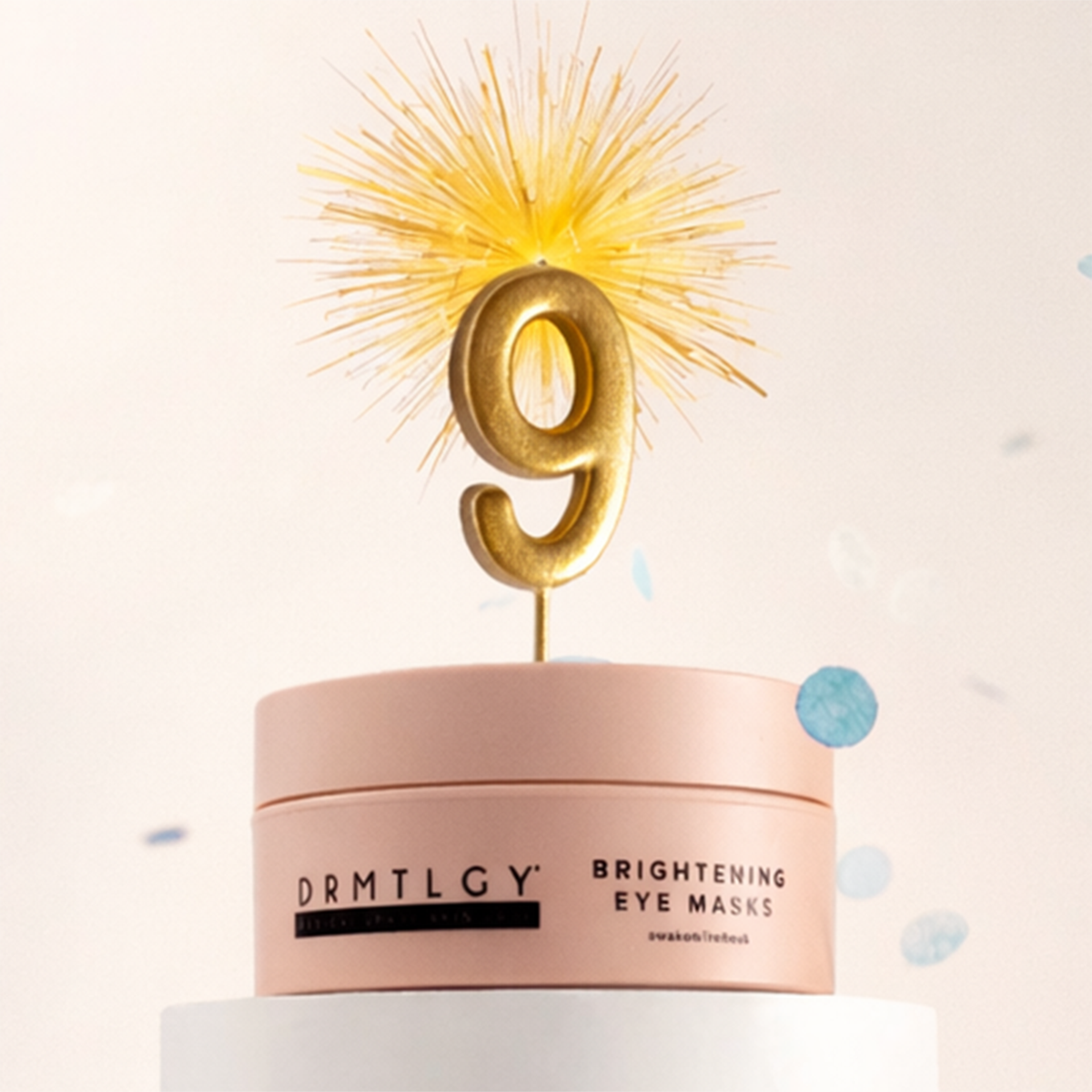 A pink jar of DRMTLGY eye masks with a golden number 9 topper and falling blue confetti.