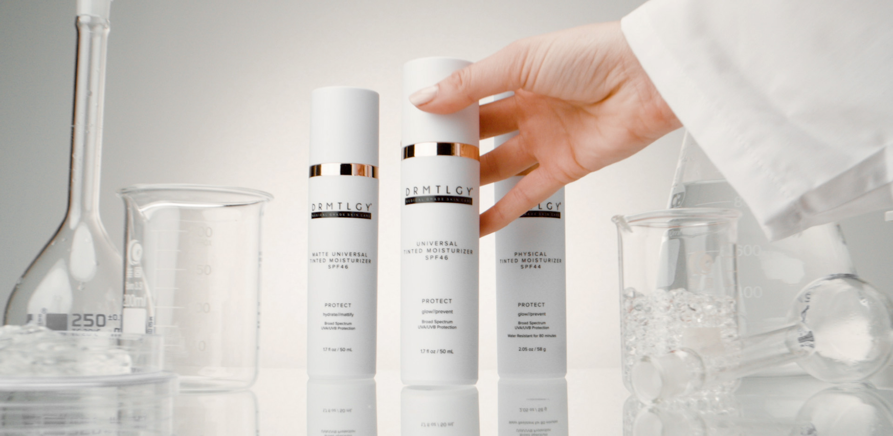 Hand reaching for skincare bottles among laboratory glassware.