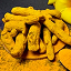 Pile of turmeric roots and powder on a dark surface.
