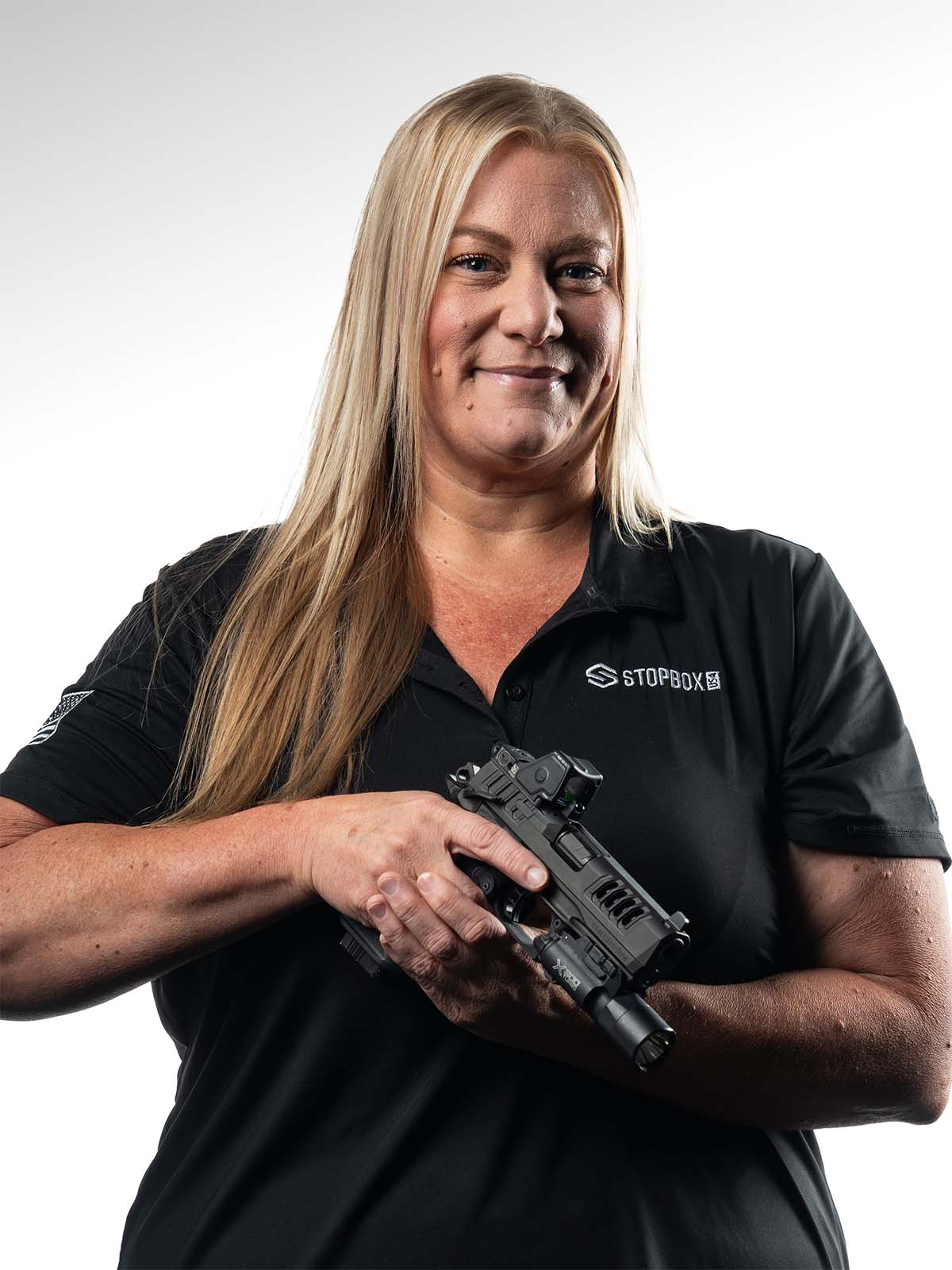 Person holding a firearm, wearing a black polo shirt with 'StopBox' logo.