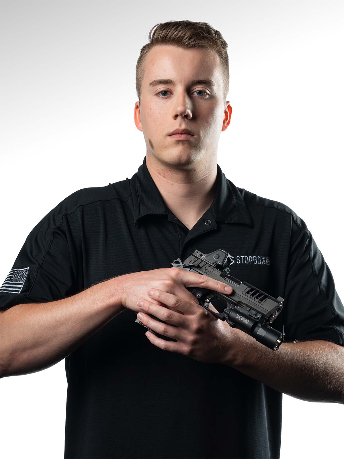 Person holding a handgun against a plain background.