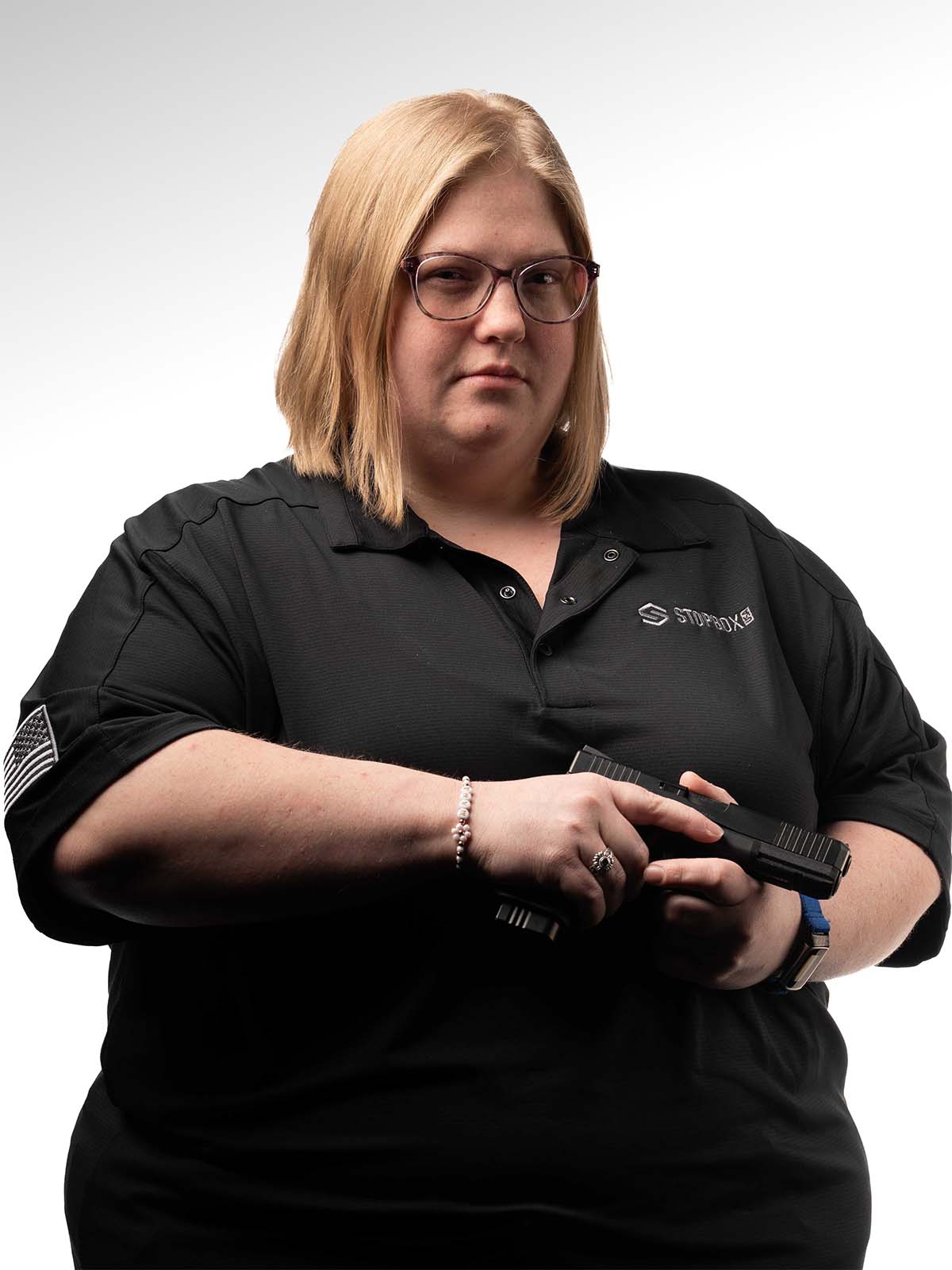 Person in a black shirt holding a black object against a white background.