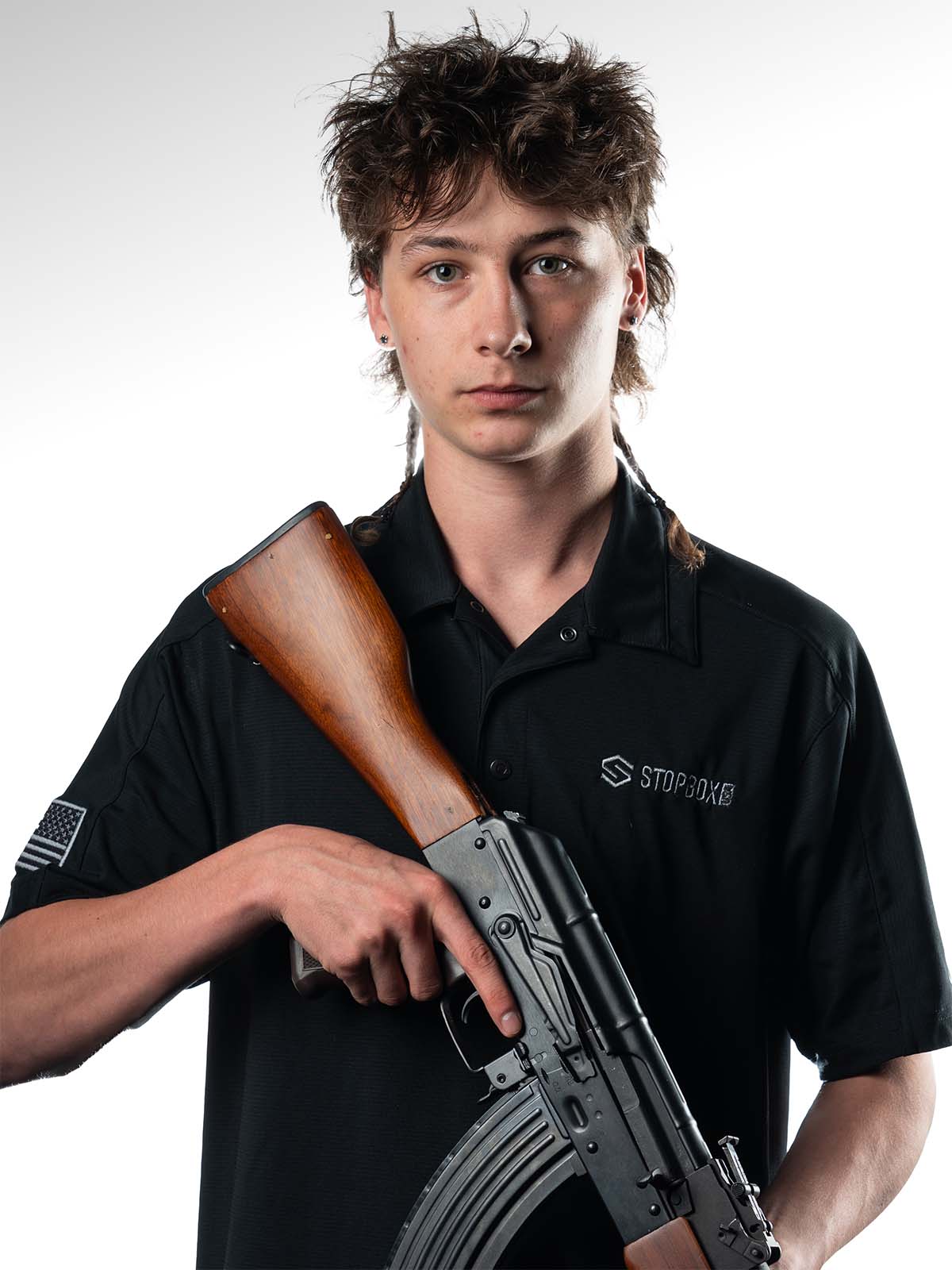 Person holding a rifle with a wooden stock, wearing a black shirt.