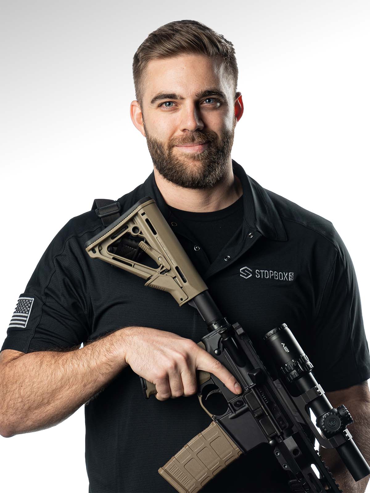 A man in a black shirt holding a rifle with a scope, on a white background.