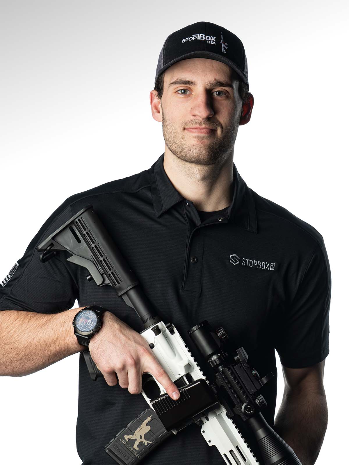 Person holding a firearm, wearing a black shirt and cap.