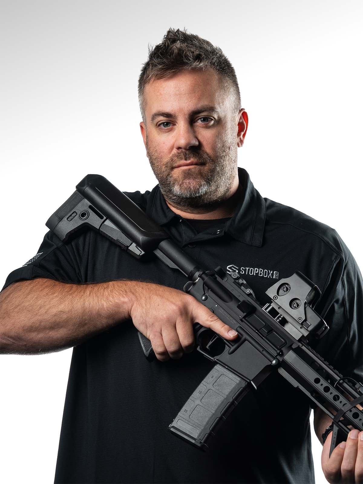 Man holding a rifle against a plain background.