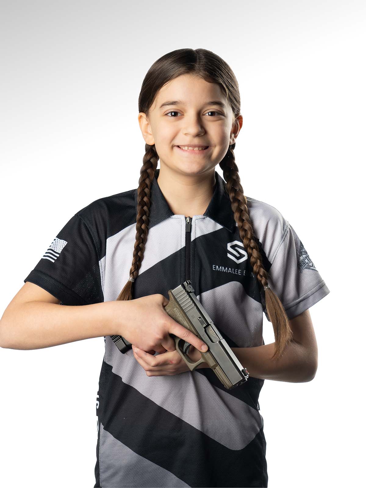 Person holding a firearm, wearing a black and gray shirt, against a white background.