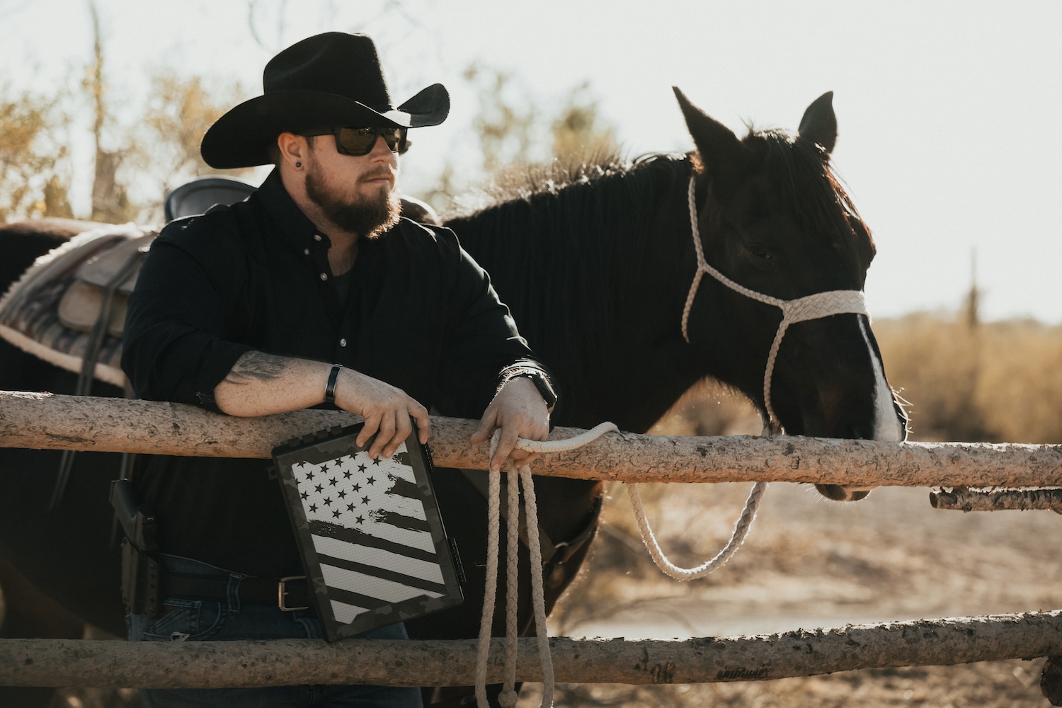 Person in cowboy hat with horse, holding an American flag tablet.
