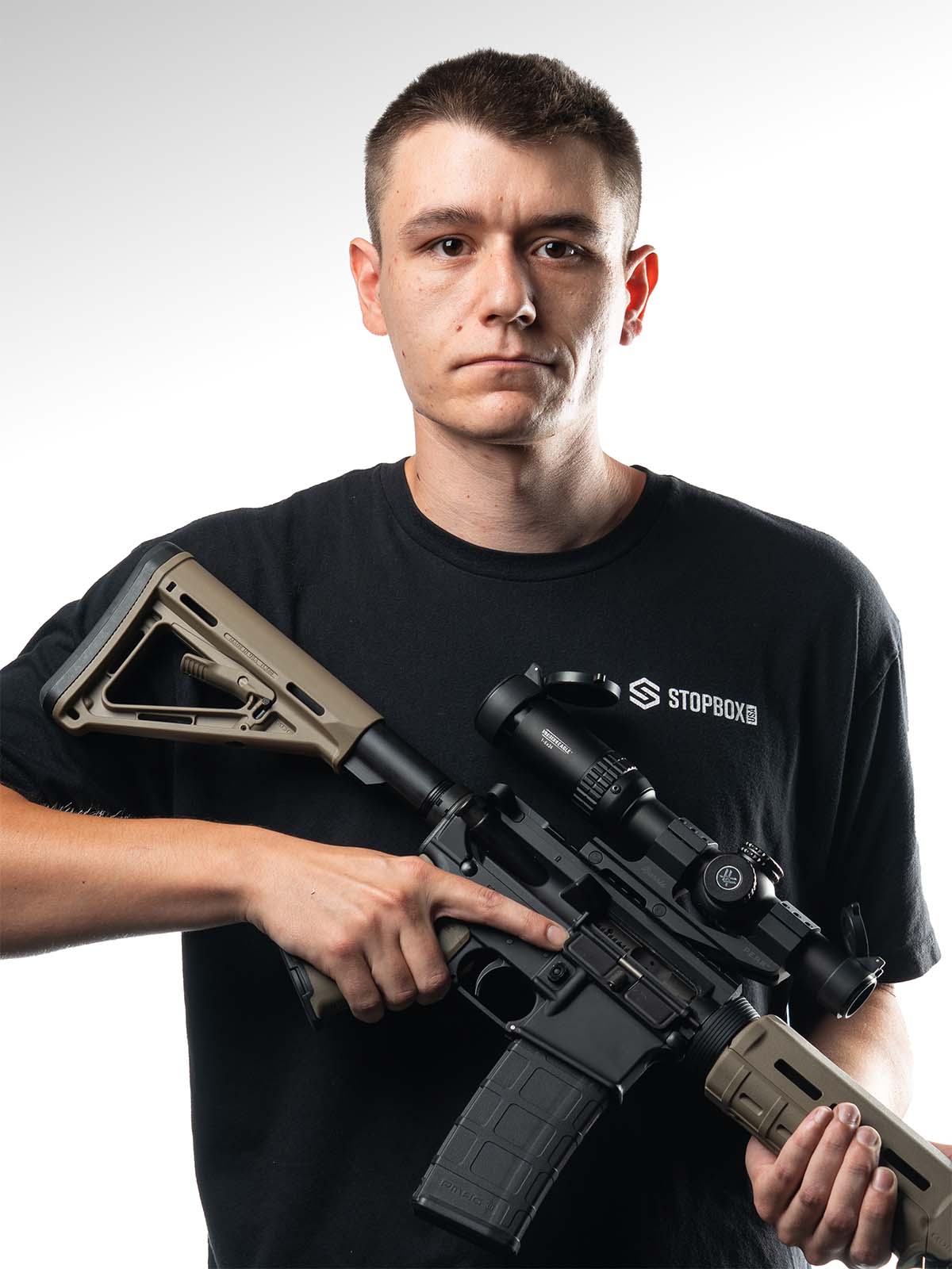 Person holding a firearm, wearing a black shirt with 'STOPBOX' logo.
