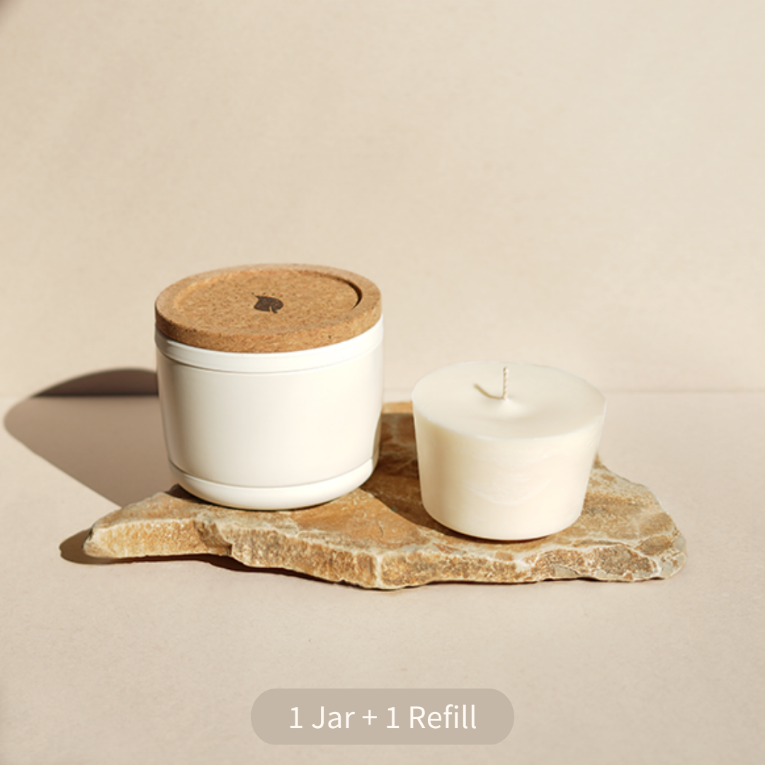 White jar with cork lid and candle on stone slab.