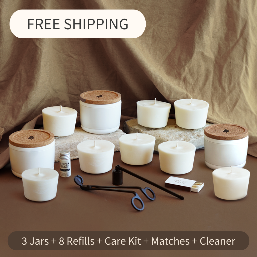 Assorted white candles with accessories on a brown fabric background.