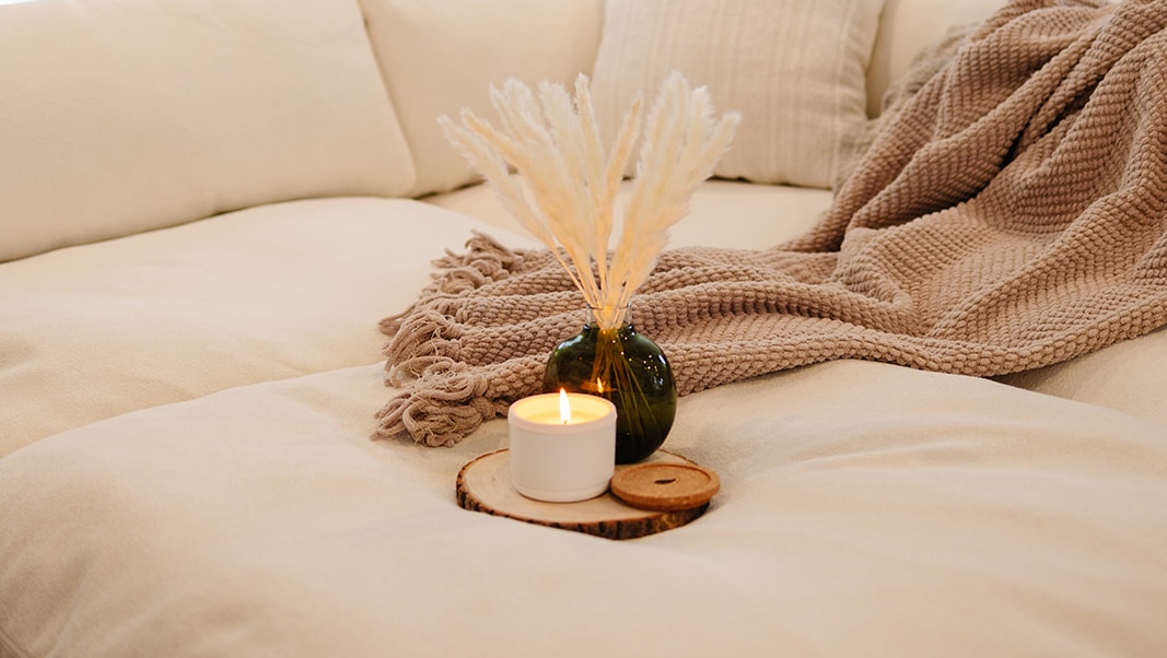 Cozy sofa with a candle, vase, and blanket.