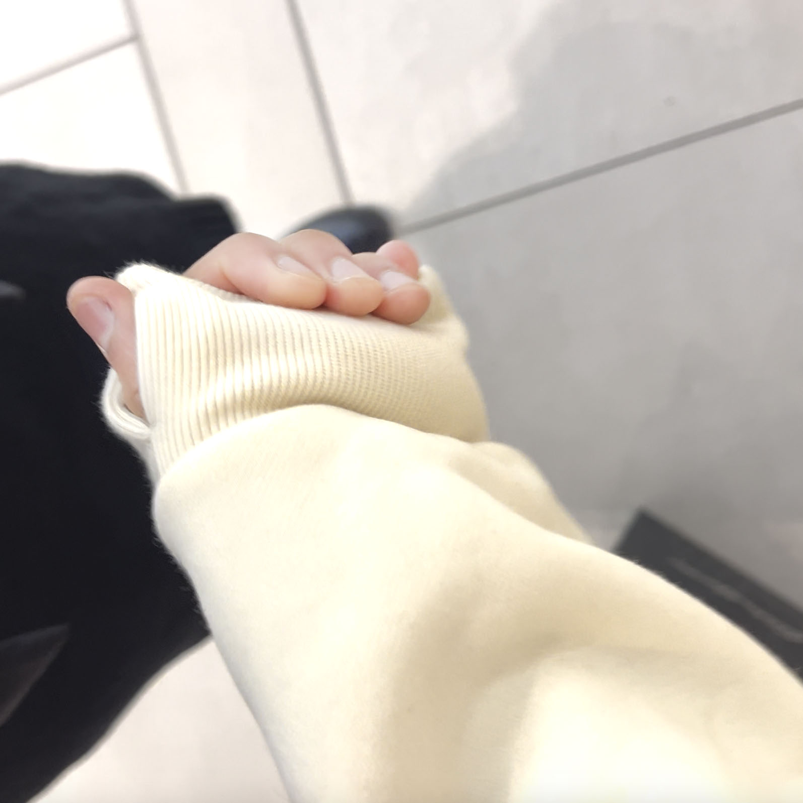 Two hands holding each other, one in a cream sleeve.