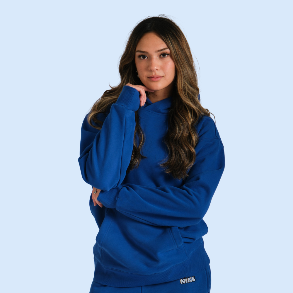 Person in a blue hoodie against a light blue background.
