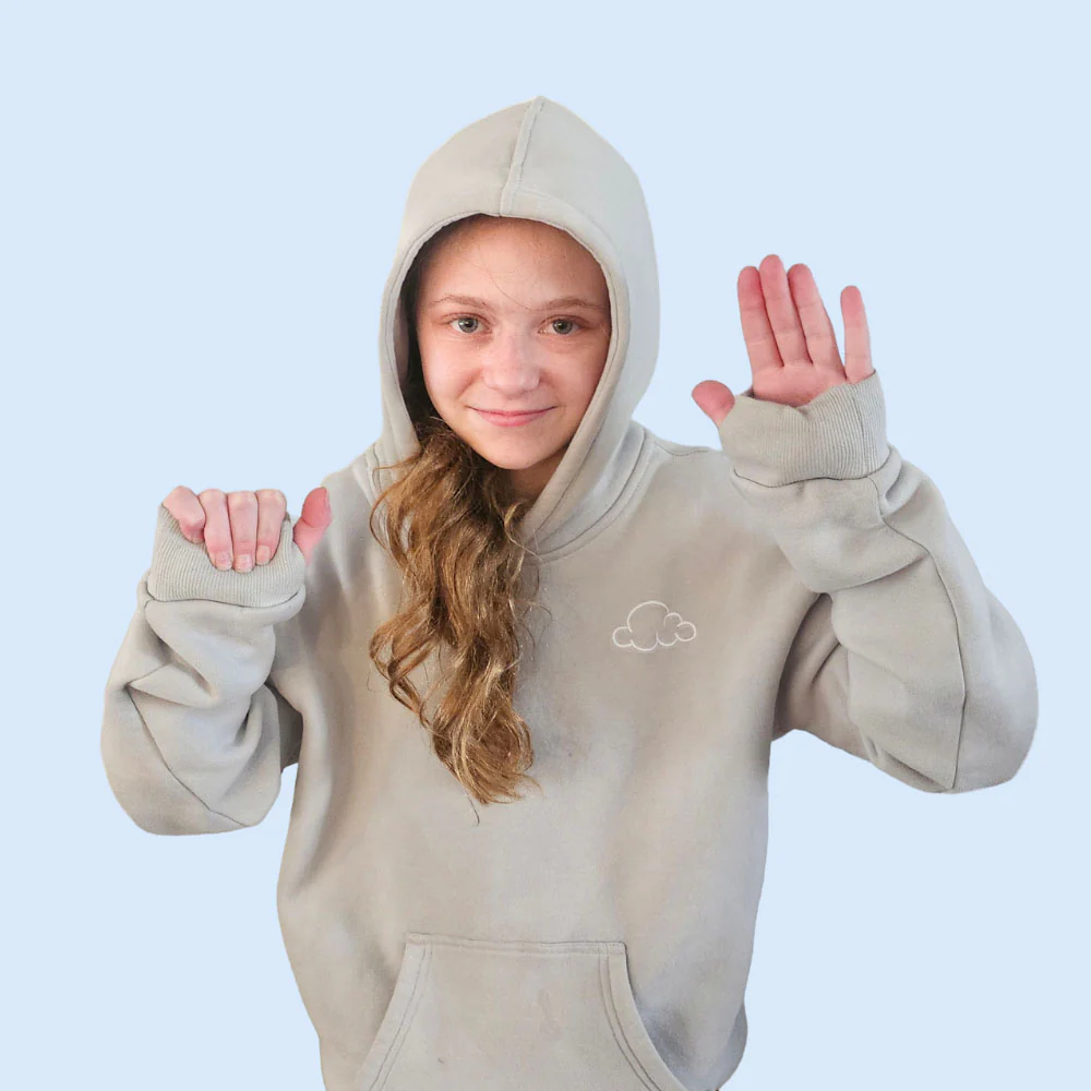 Person in a gray hoodie with a cloud logo, raising hands playfully.
