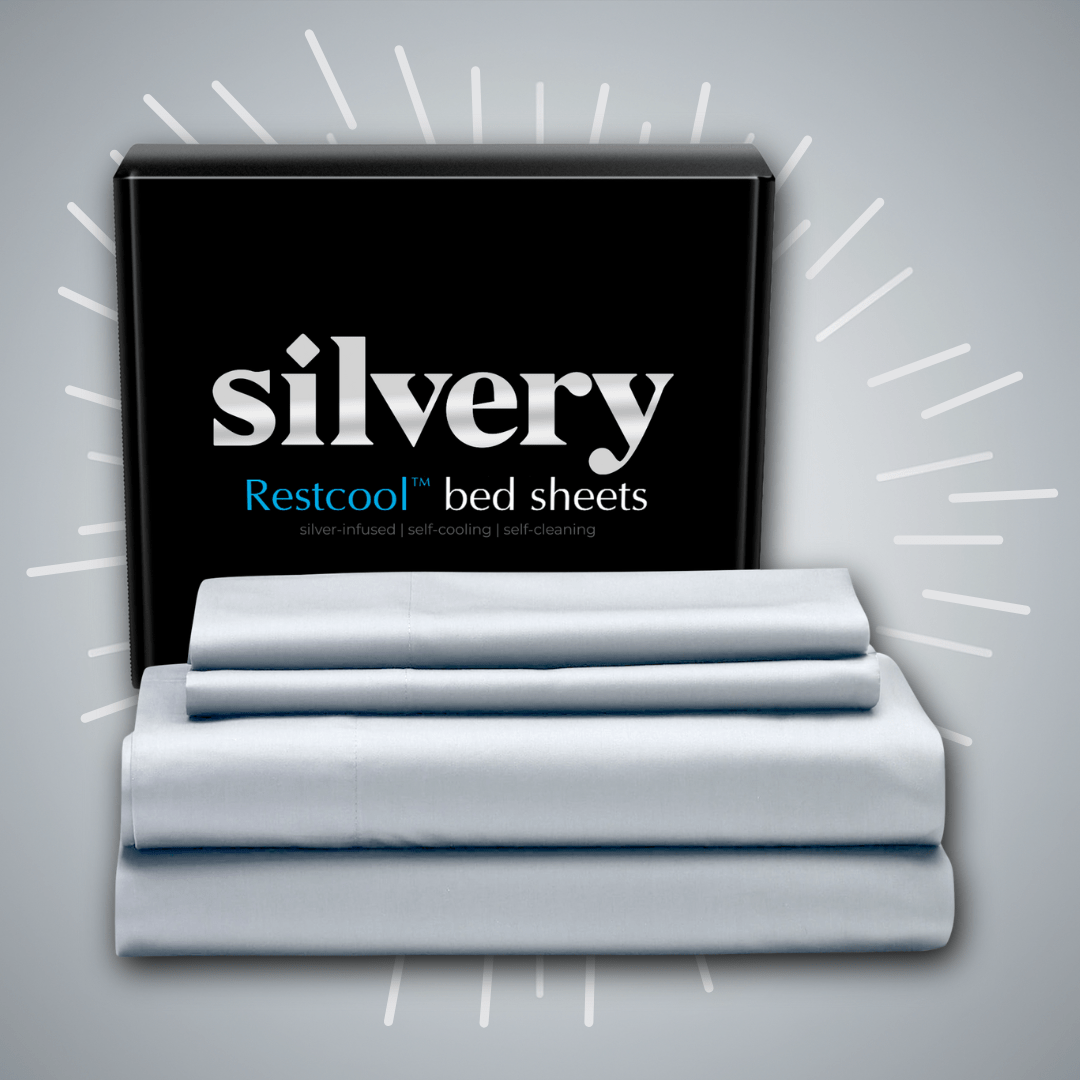 Stack of folded bed sheets in front of a box labeled 'silvery Restcool bed sheets.'