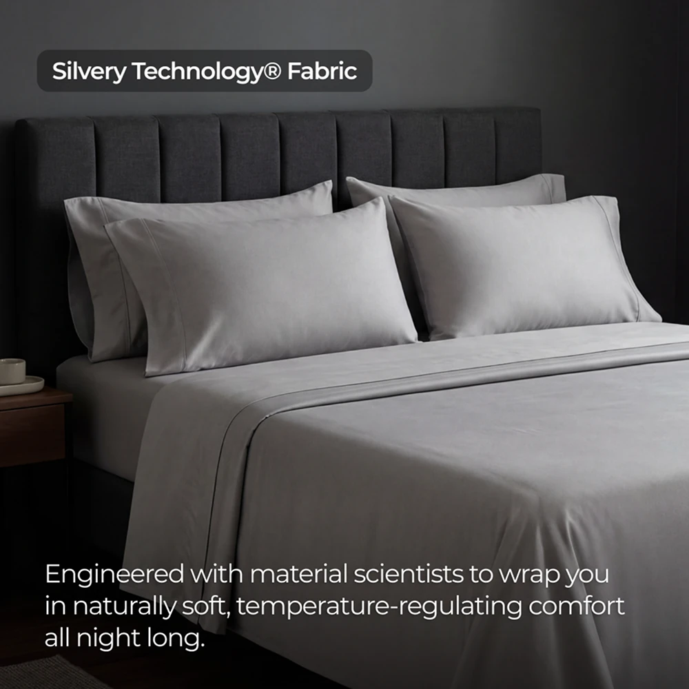 A neatly made bed with light gray sheets and pillowcases against a dark gray, tufted headboard.