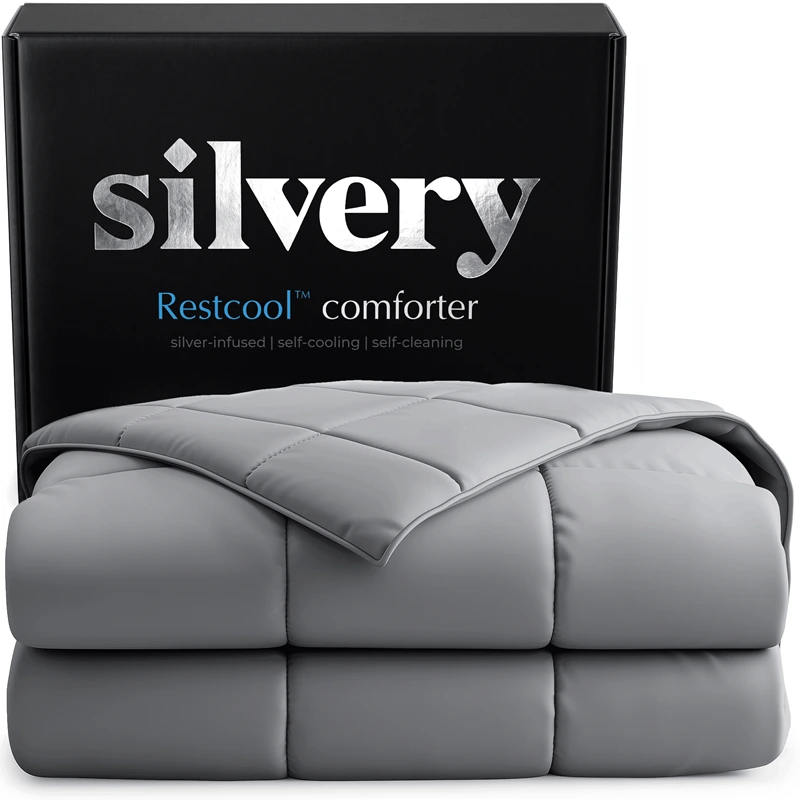 A folded, gray Silvery Restcool comforter sits in front of its black packaging box on a white surface.