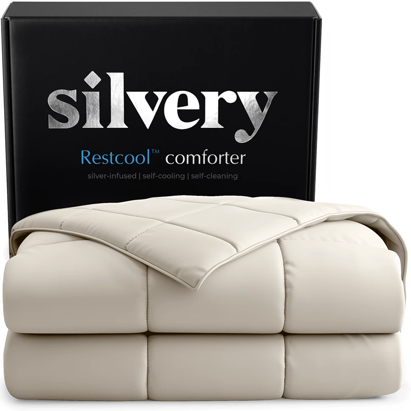 A folded, off-white quilted comforter is displayed in front of its black product box from Silvery.