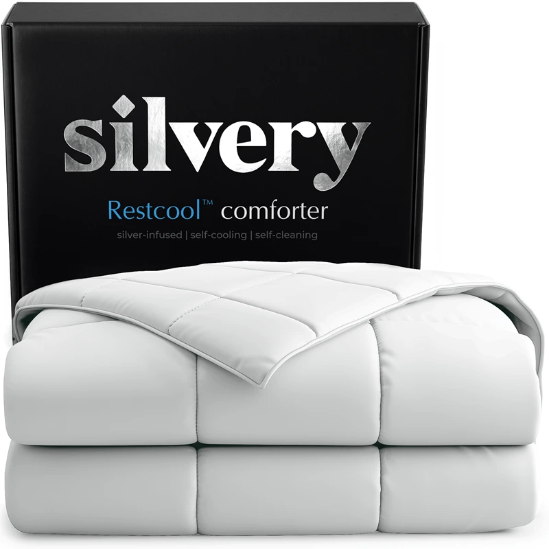 A white, folded Silvery Restcool comforter is displayed in front of its black packaging box.