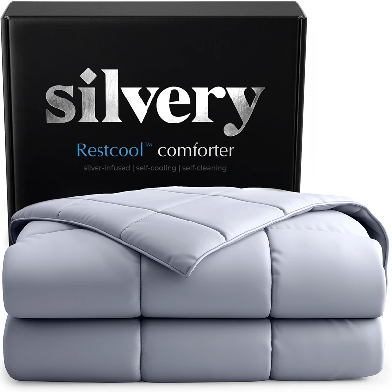 A folded, light gray quilted comforter is displayed in front of its black packaging box from the brand Silvery.