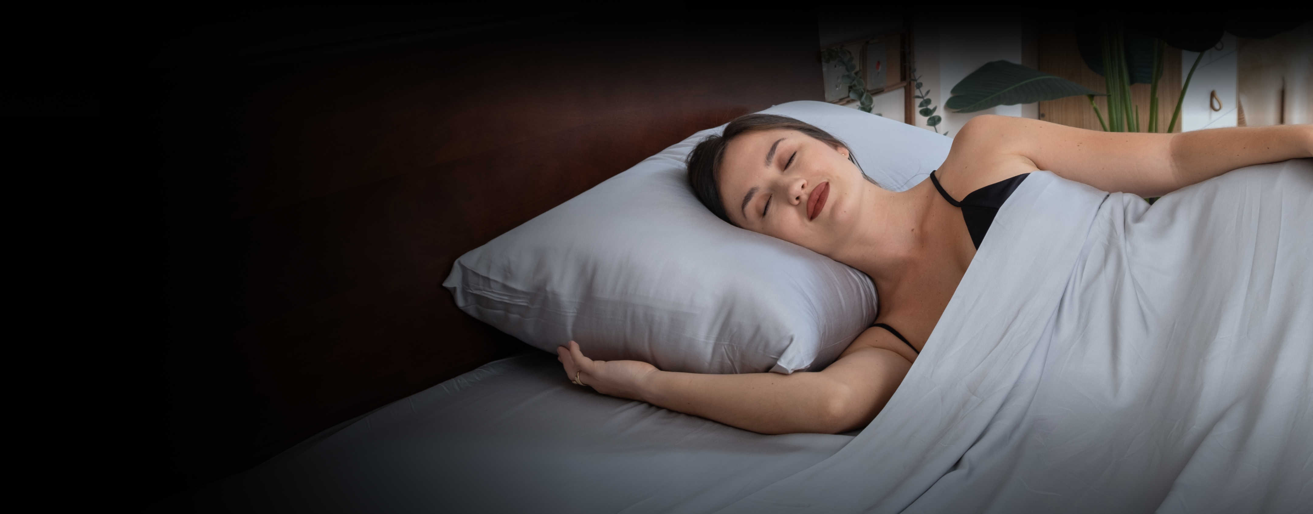 Person sleeping peacefully on a bed with white pillow and sheets.