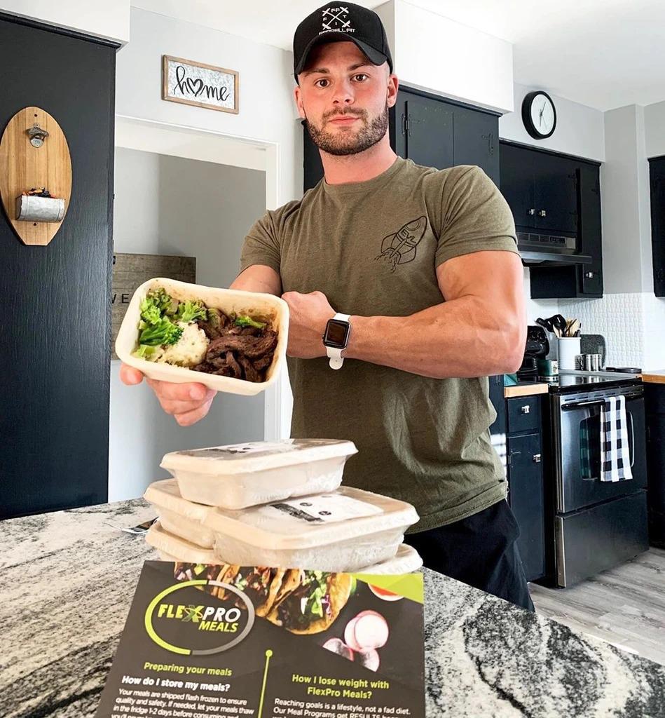 Man holding a meal container in a kitchen with FlexPro Meals packaging.