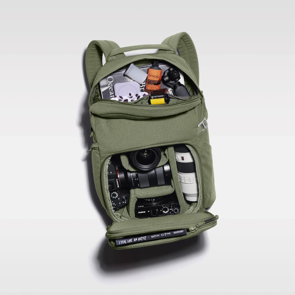 A green backpack filled with camera equipment and accessories.