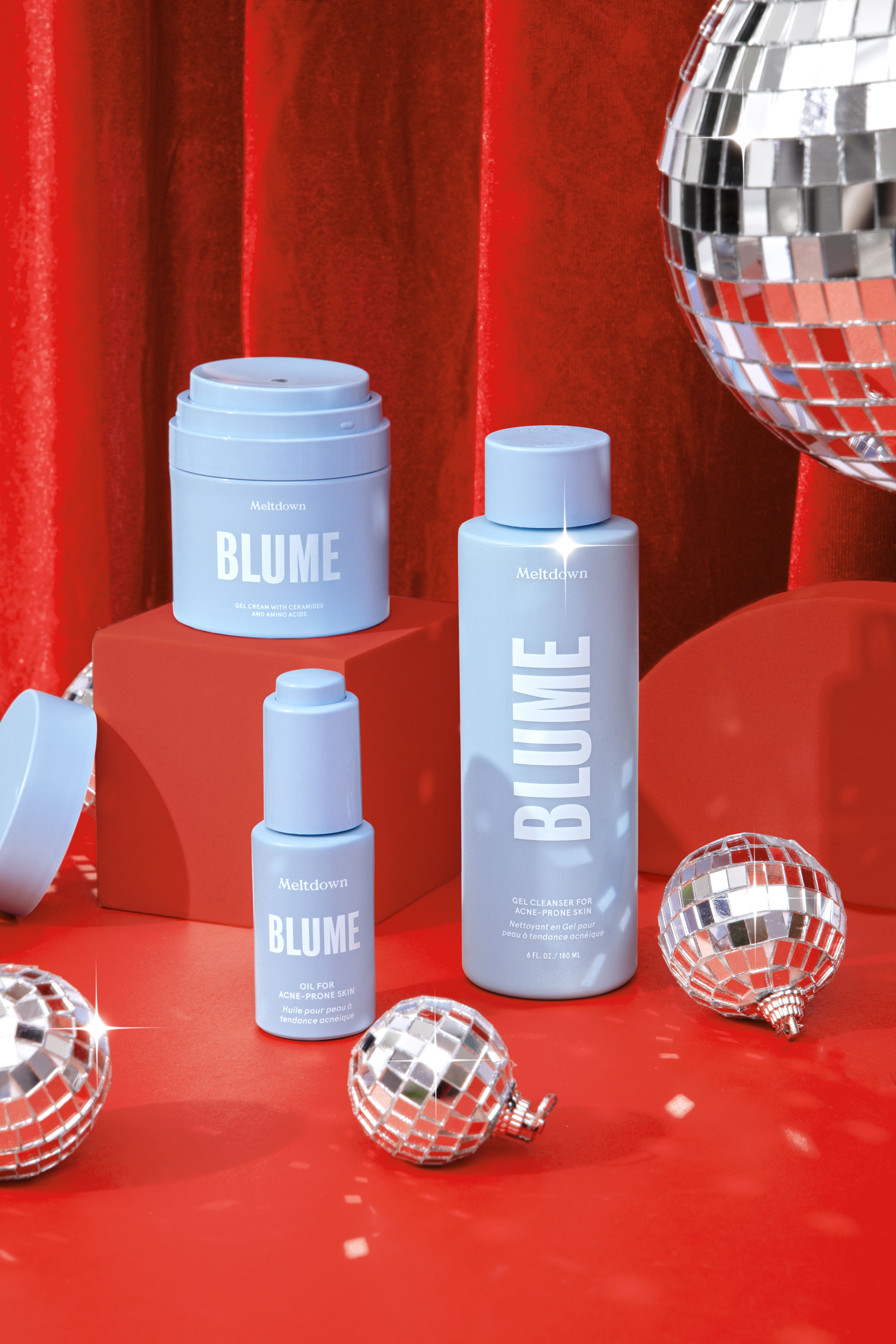 Blue skincare products with disco balls and red background.