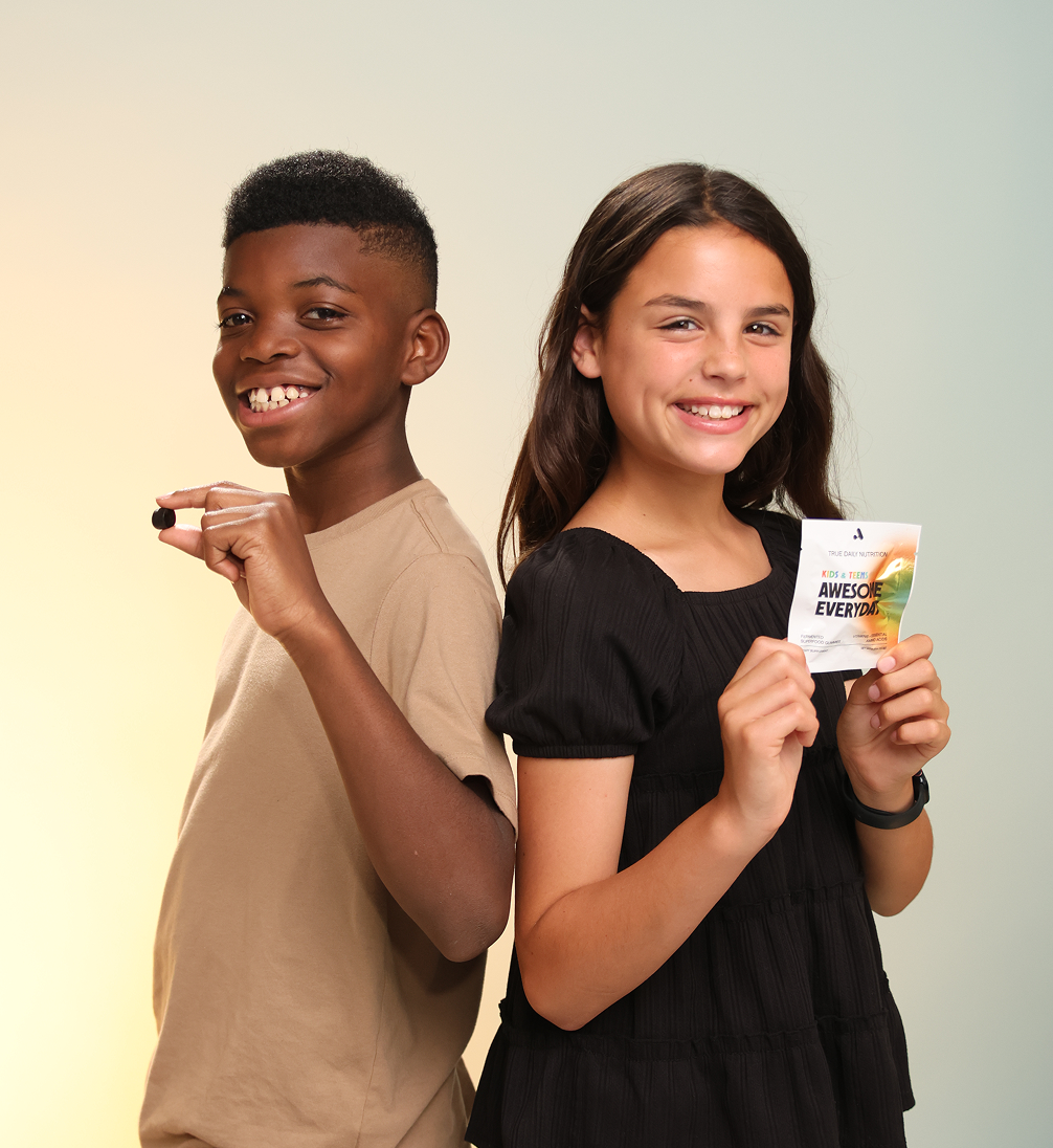Two smiling children holding a small object and a packet.