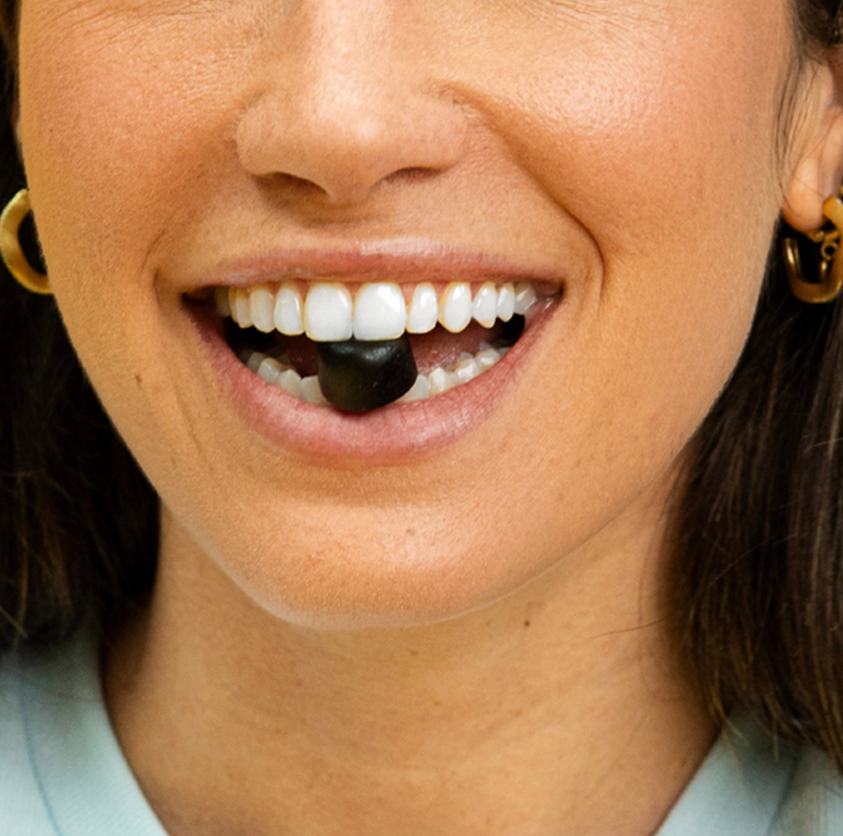 Person smiling with a black object between teeth.