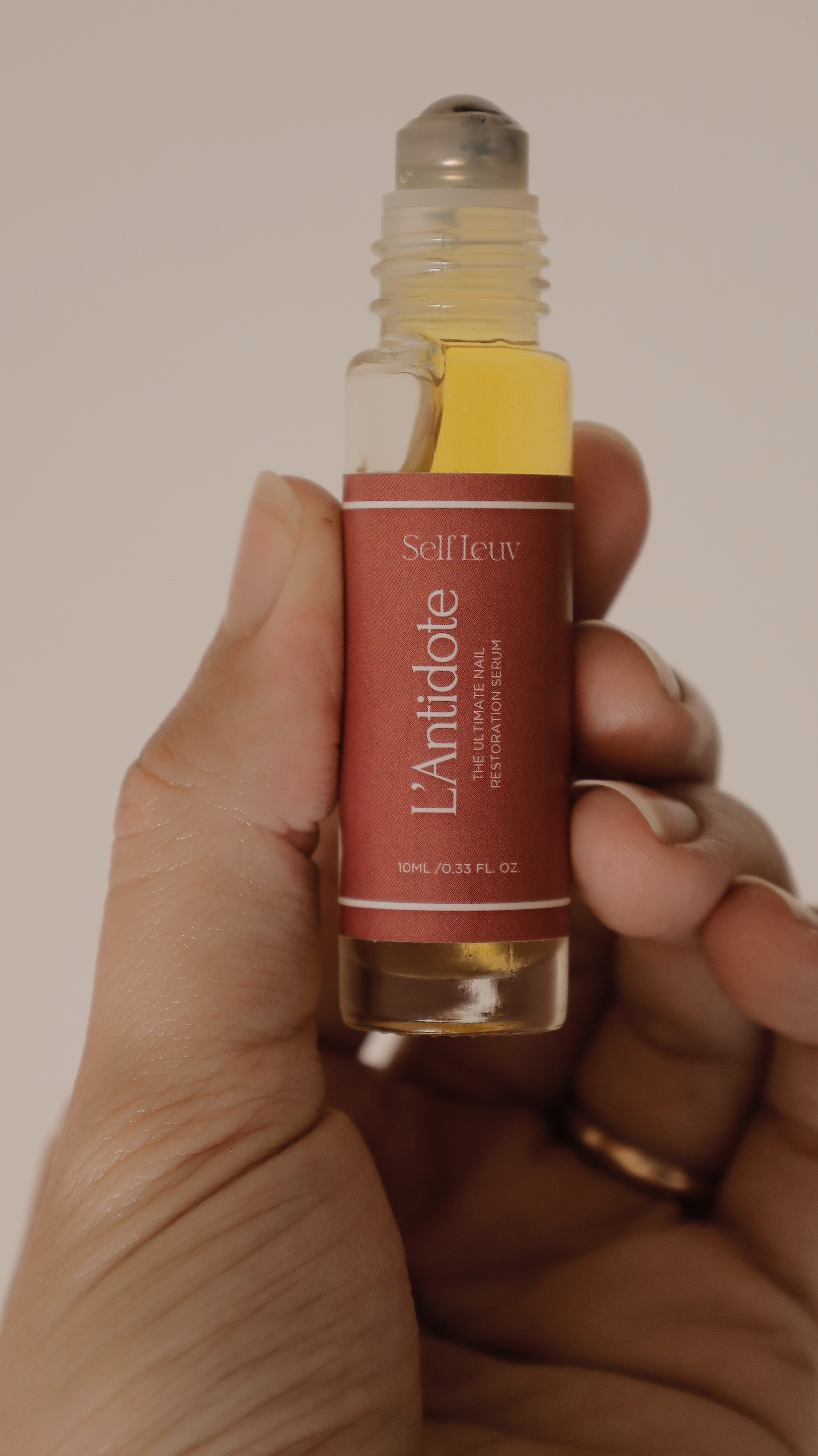 Hand holding a small bottle labeled 'L'Antidote' with a rollerball top.