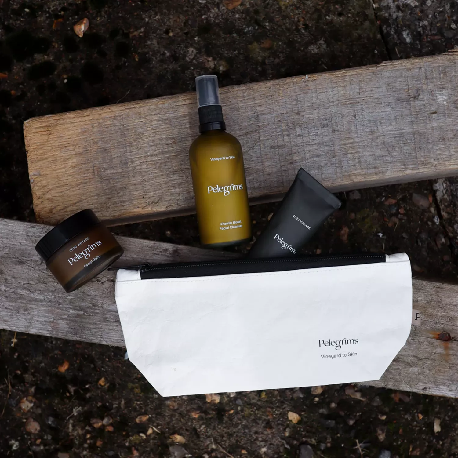 Four skincare products arranged on wooden planks outdoors.