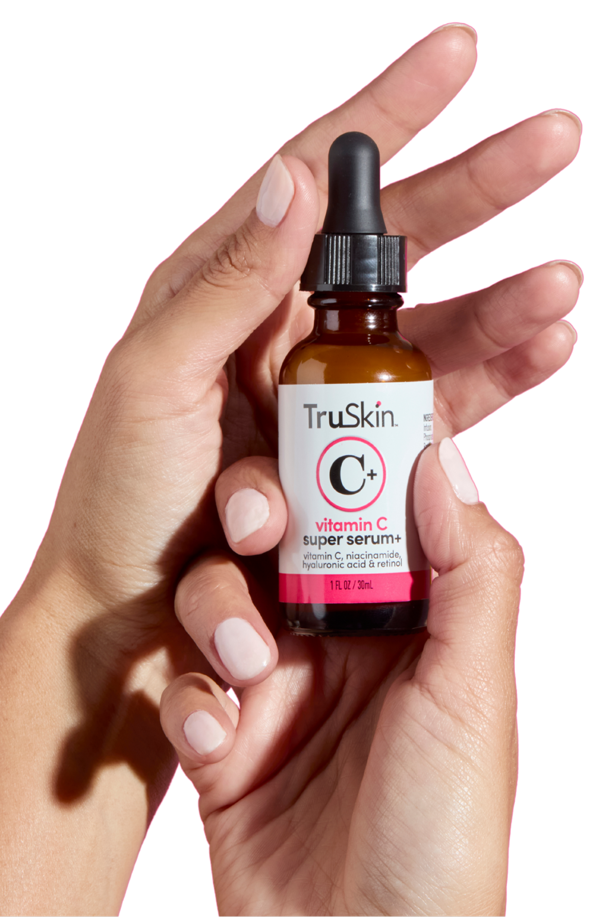 A pair of hands with light pink nails holds a bottle of TruSkin Vitamin C Super Serum+.