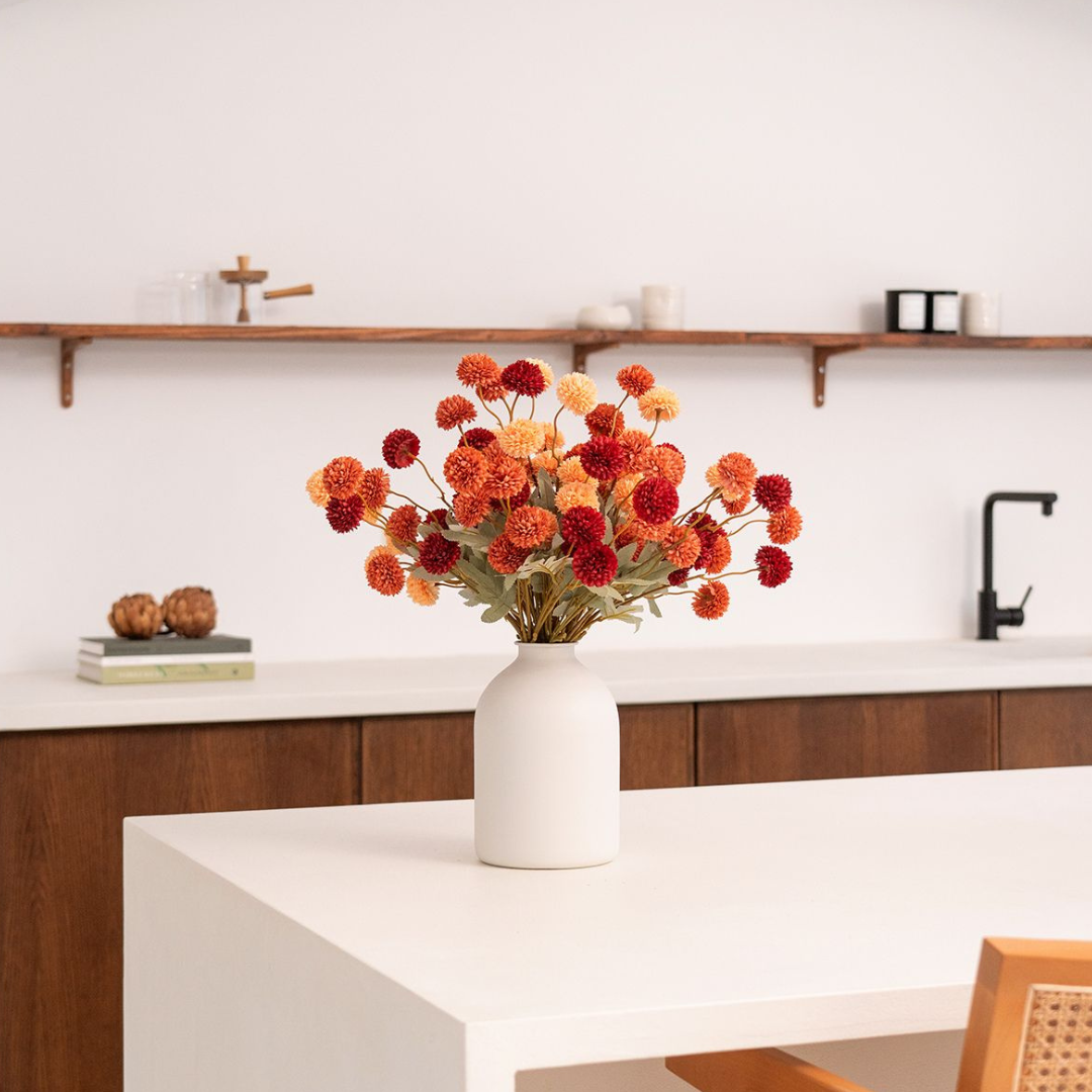 Vase with red and orange flowers on a white kitchen counter.