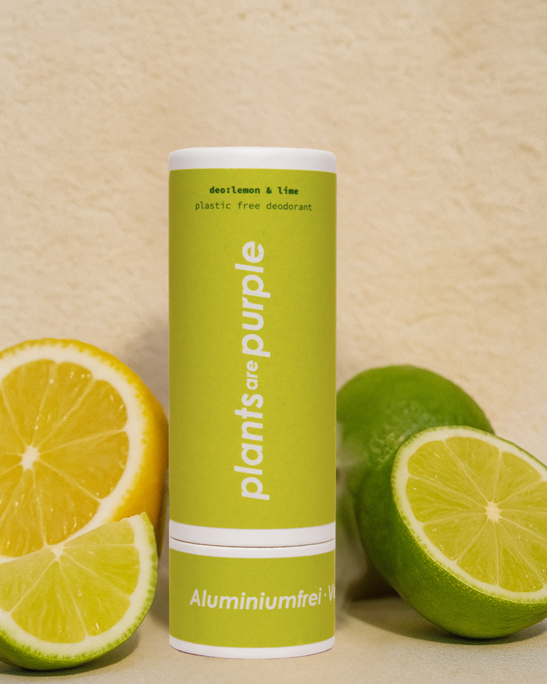 Green deodorant tube with lemon and lime slices on a beige background.