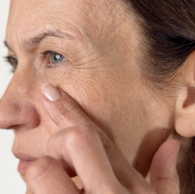 Close-up of a person touching their cheek near the eye.