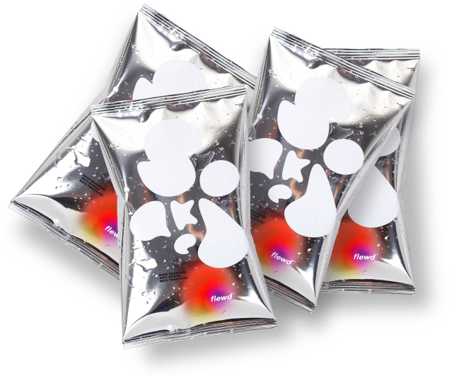Four shiny silver packets with white abstract designs and water droplets scattered on a white background.