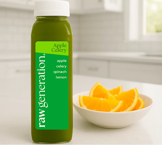 Green juice bottle labeled 'Apple Celery' next to a bowl of orange slices.