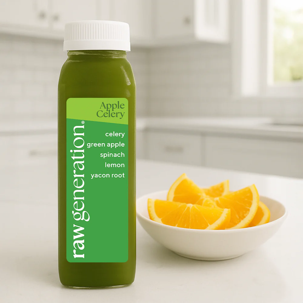 A bottle of Raw Generation green juice sits on a kitchen counter next to a bowl of orange slices.