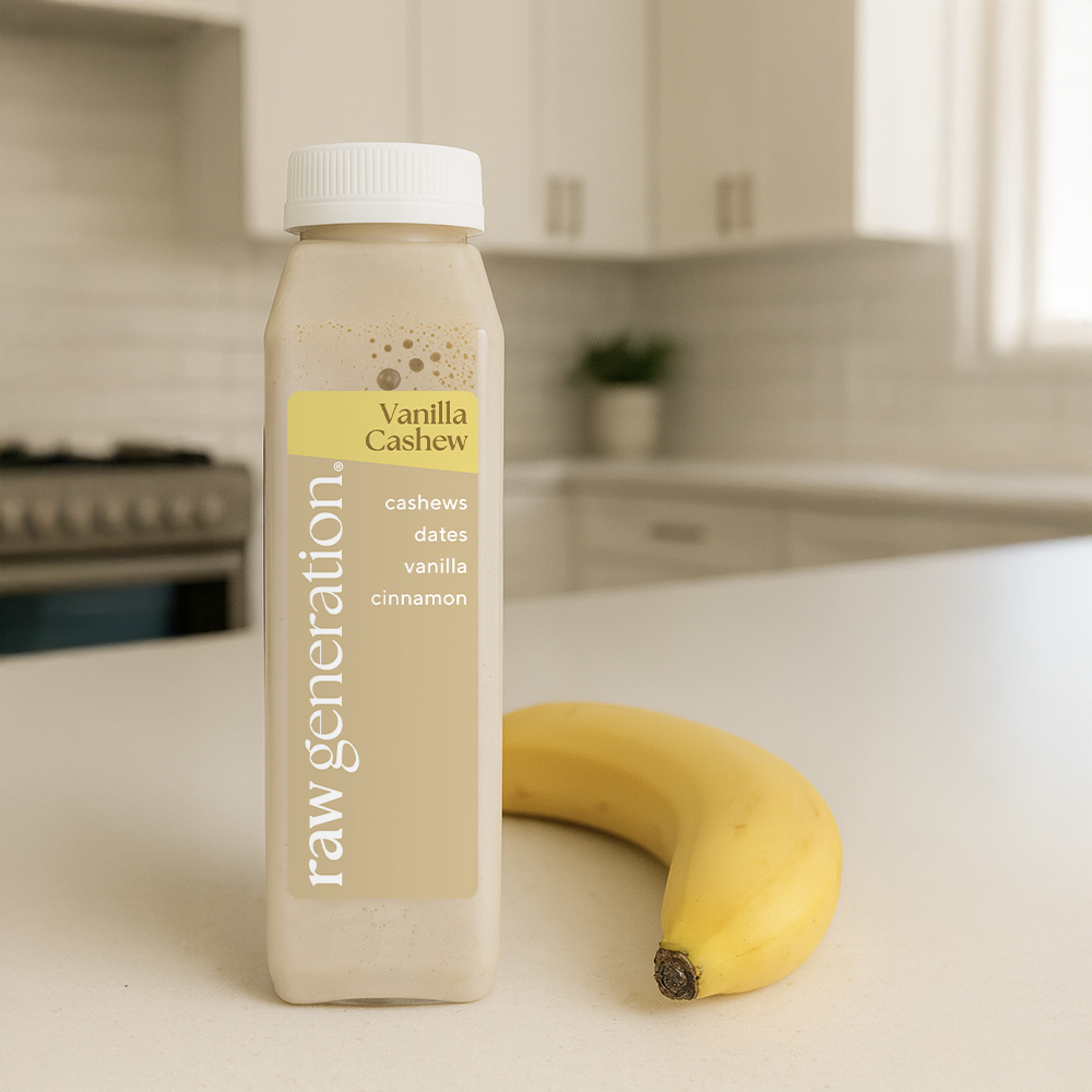 A bottle of Raw Generation Vanilla Cashew drink sits next to a banana on a kitchen counter.