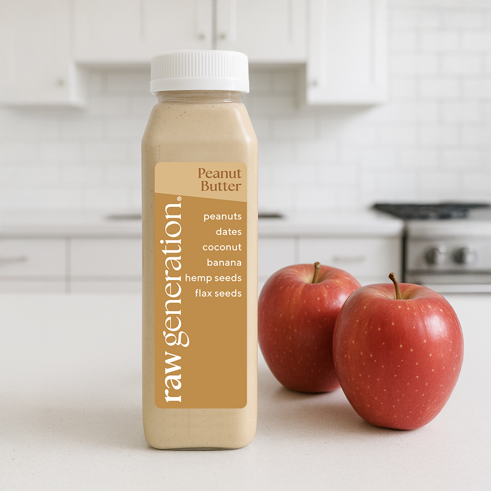 A bottle of Raw Generation Peanut Butter drink sits on a kitchen counter next to two red apples.