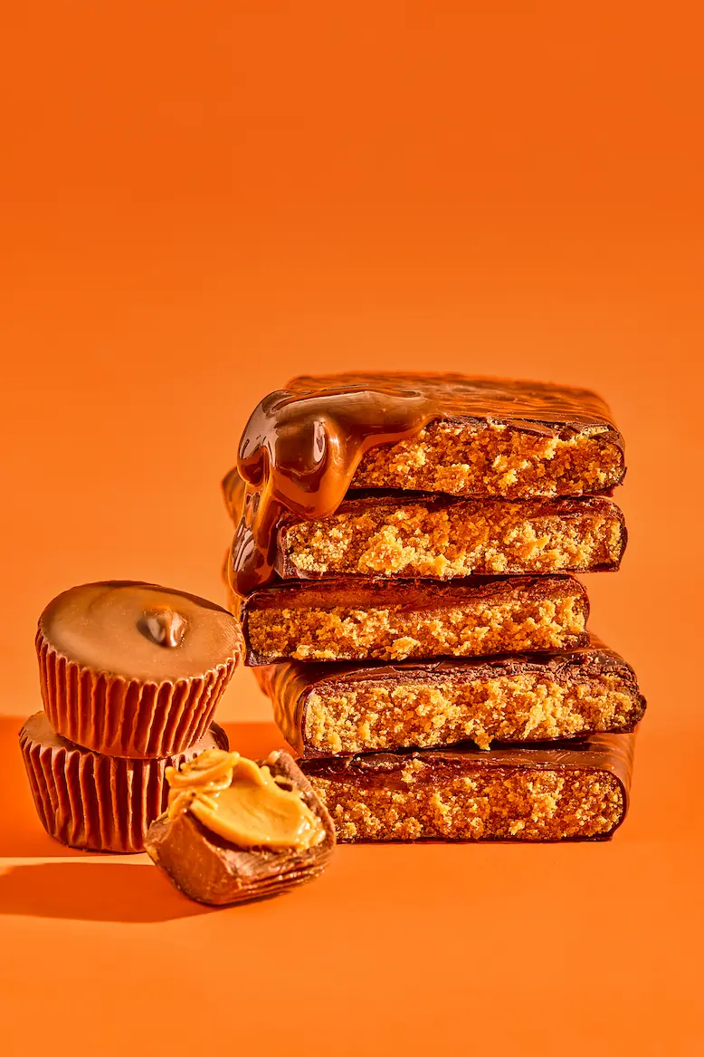 Stack of chocolate bars with peanut butter cups on orange background.