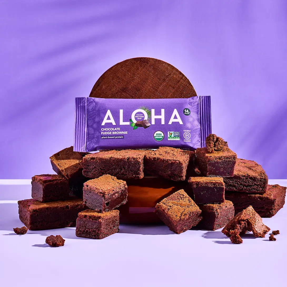 Stack of chocolate brownies with a purple Aloha wrapper on a purple background.