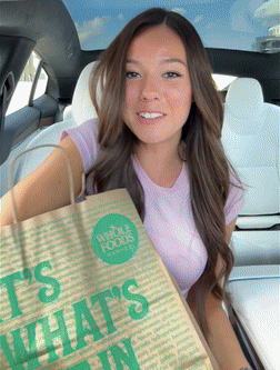 Person holding a grocery bag inside a car.