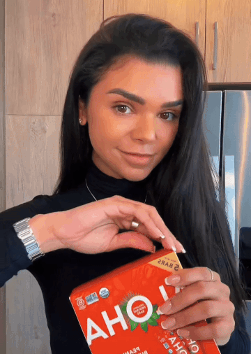 Person holding an OHA candy package in a kitchen.